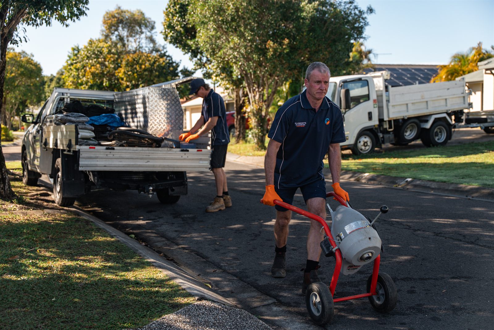 Elements Plumbing wheeling a drain-cleaning machine to a job on the Sunshine Coast